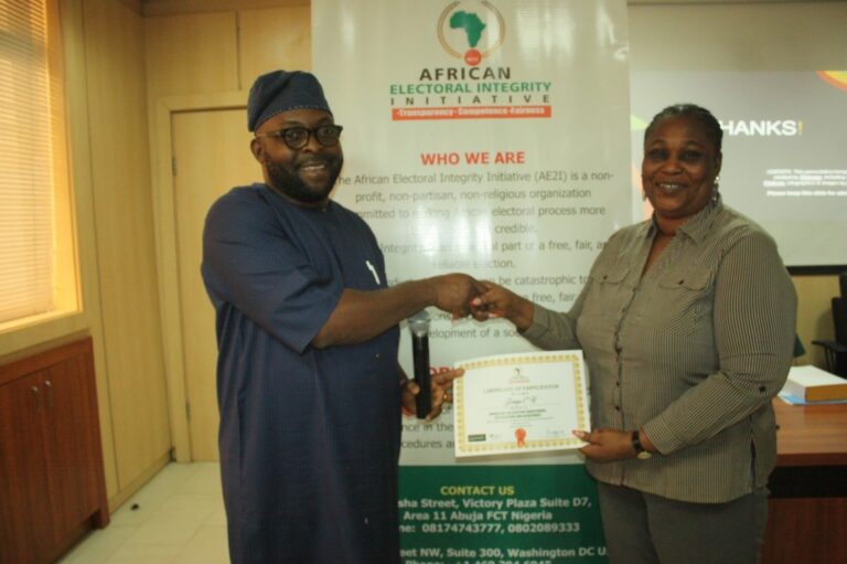 Dr. Daniel Omofoman presenting a Certificate of Participation to Mrs. Helen C. Garpiya Deputy-Director Department of Political Research and Constitutional Matters (PRCM-OSGF).