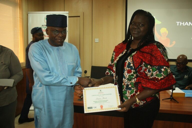 Mr. Joseph Oluwole Samuel Director Department of Political Research and Constitutional Matters (PRCM-OSGF) presenting a Certificate of Participation to Mrs. Jaiyesimi Aderonke.